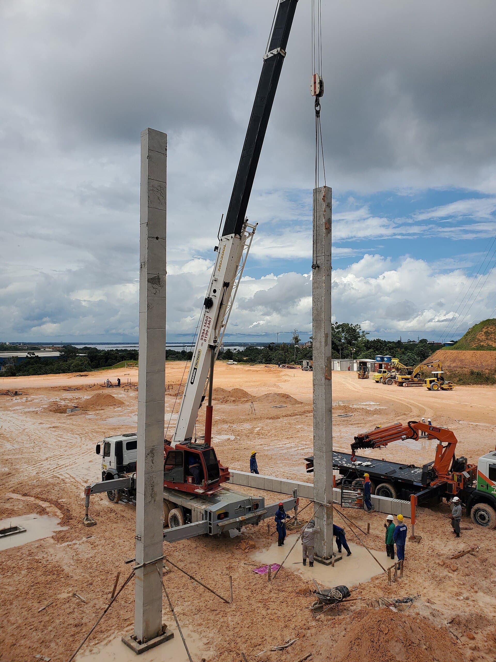Coluna pré-moldada de concreto sendo posicionada por guindaste